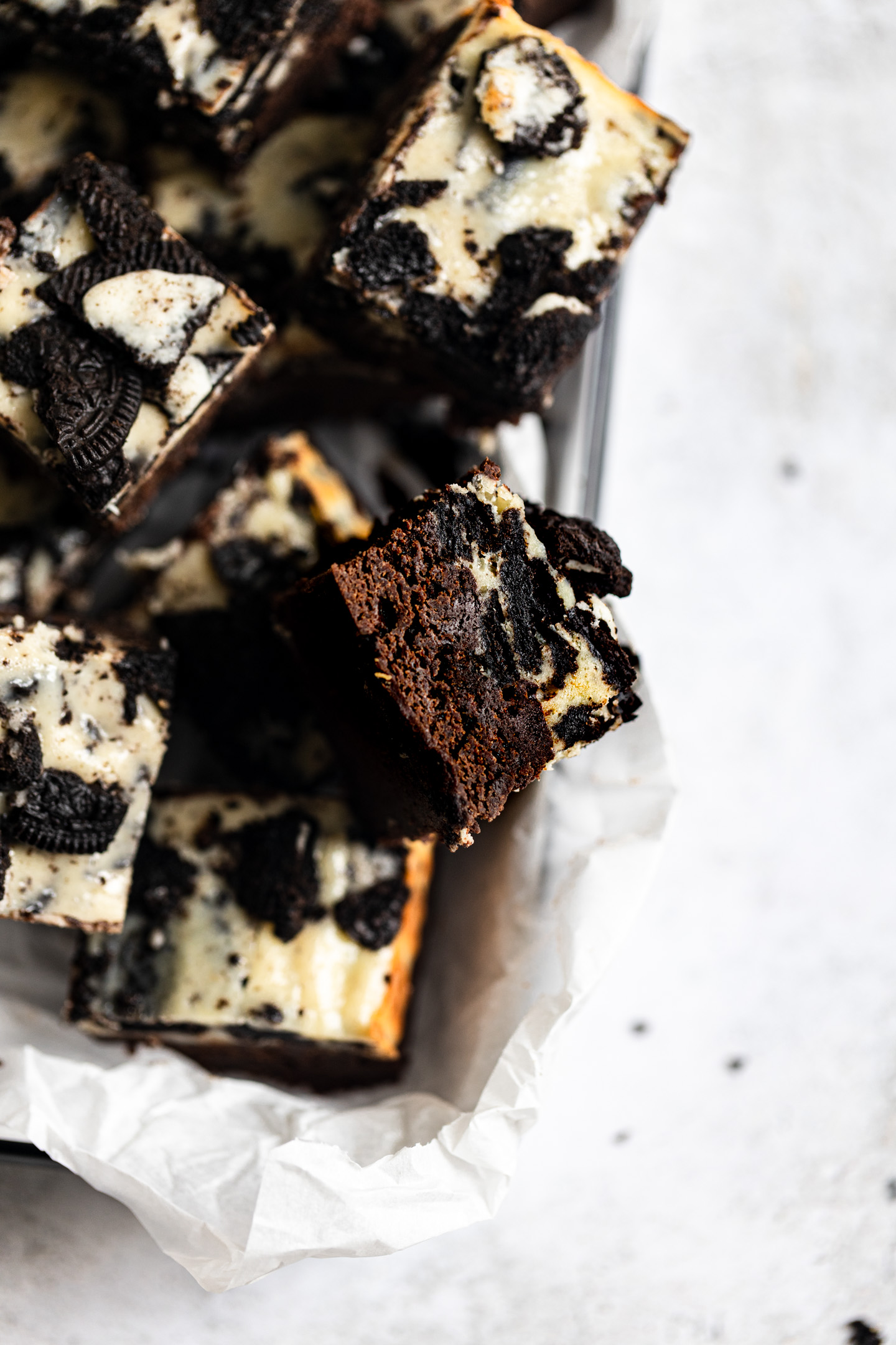 A Oreo Cheesecake brownie on its side next to other brownies in a tin.