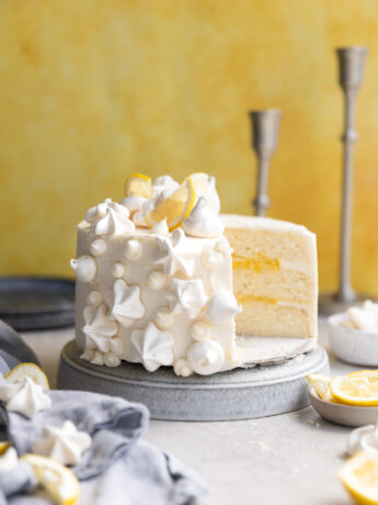 A lemon curd cake with a slice taken out of it.