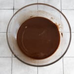 Melted chocolate in a glass bowl on a tile surface.