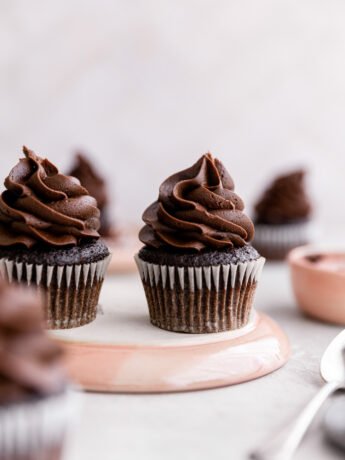 Chocolate fudge cupcakes on an overturned pink plate.