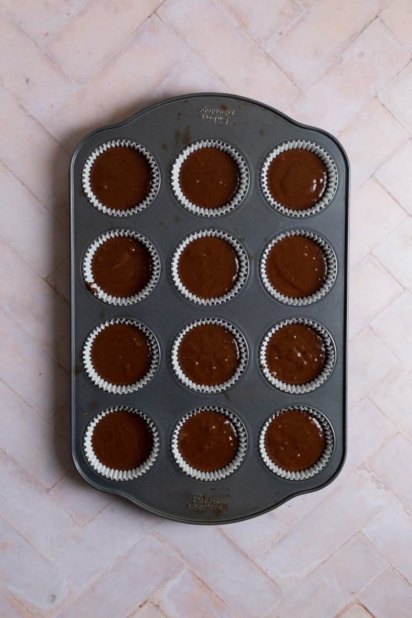 Chocolate fudge cupcake batter in a muffin tin.