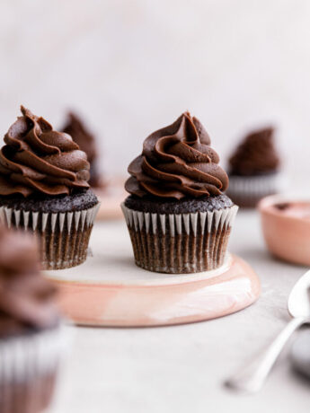 Chocolate fudge cupcakes on an overturned pink plate.