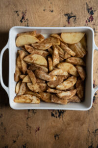 Apples tossed in brown sugar in a baking dish.