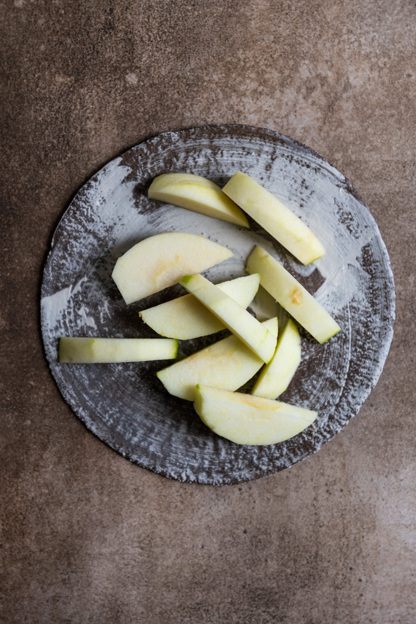 Slices of apples on a brown and white plate.