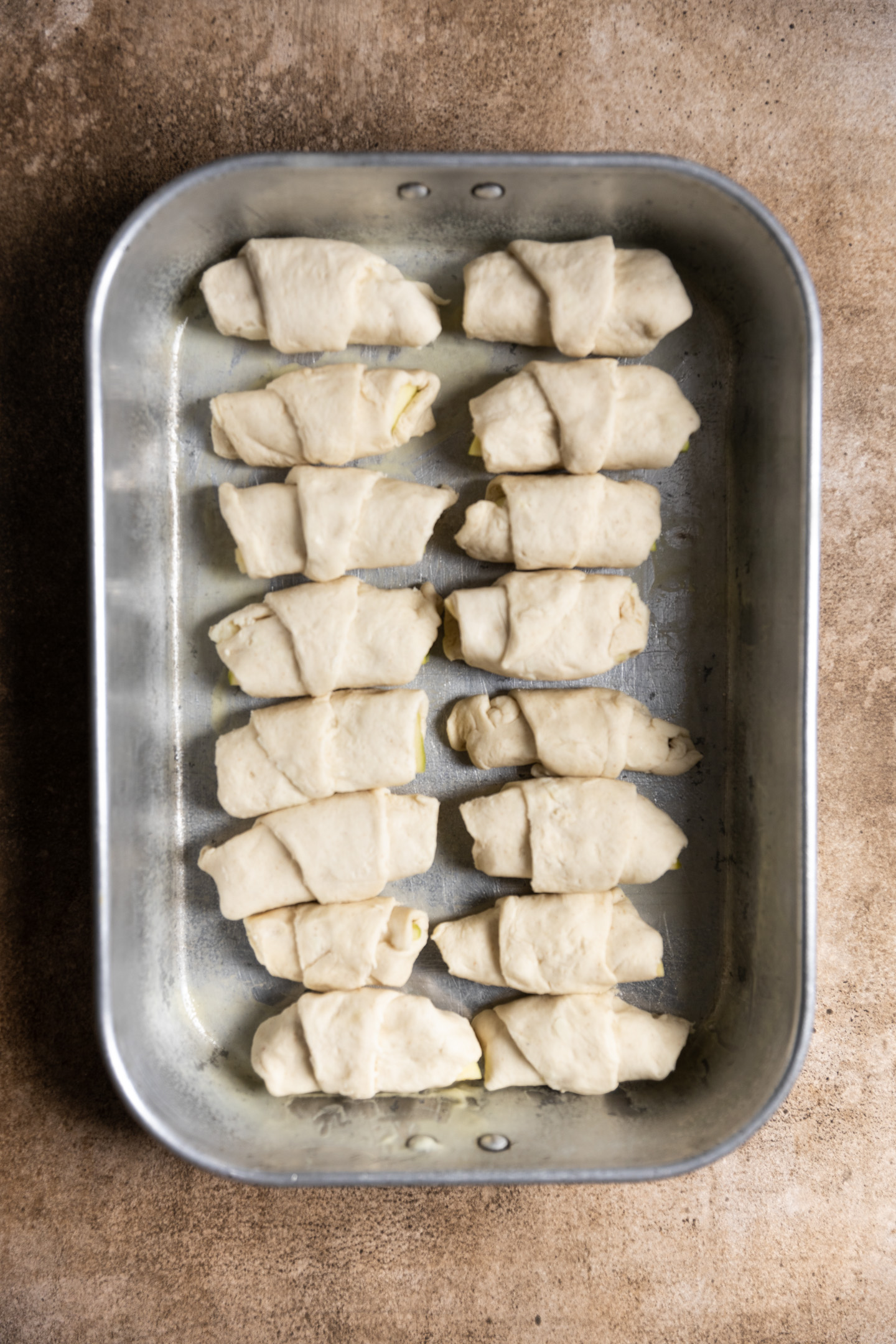 Unbaked and wrapped dumplings in a baking pan.