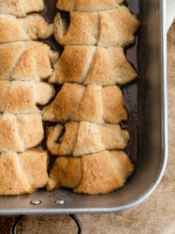 Apple dumplings lined up and baked in a pan.