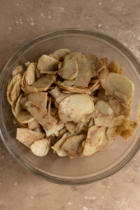 Thinly sliced and spiced apples in a large glass bowl.
