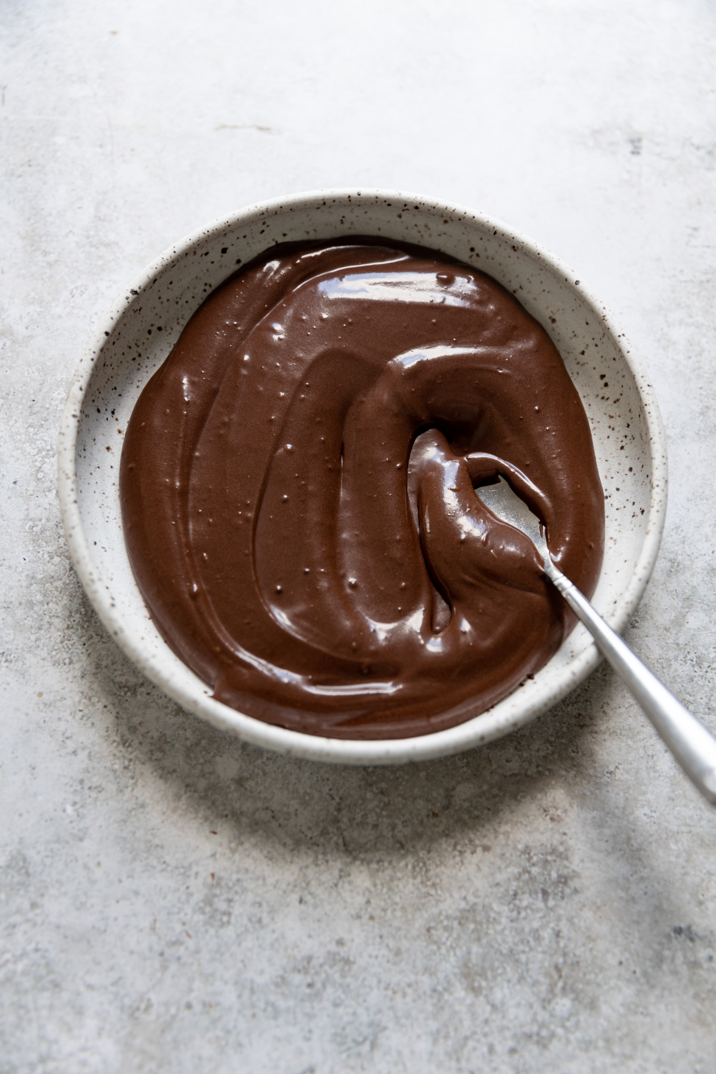 Chocolate glaze in a shallow bowl with a spoon.