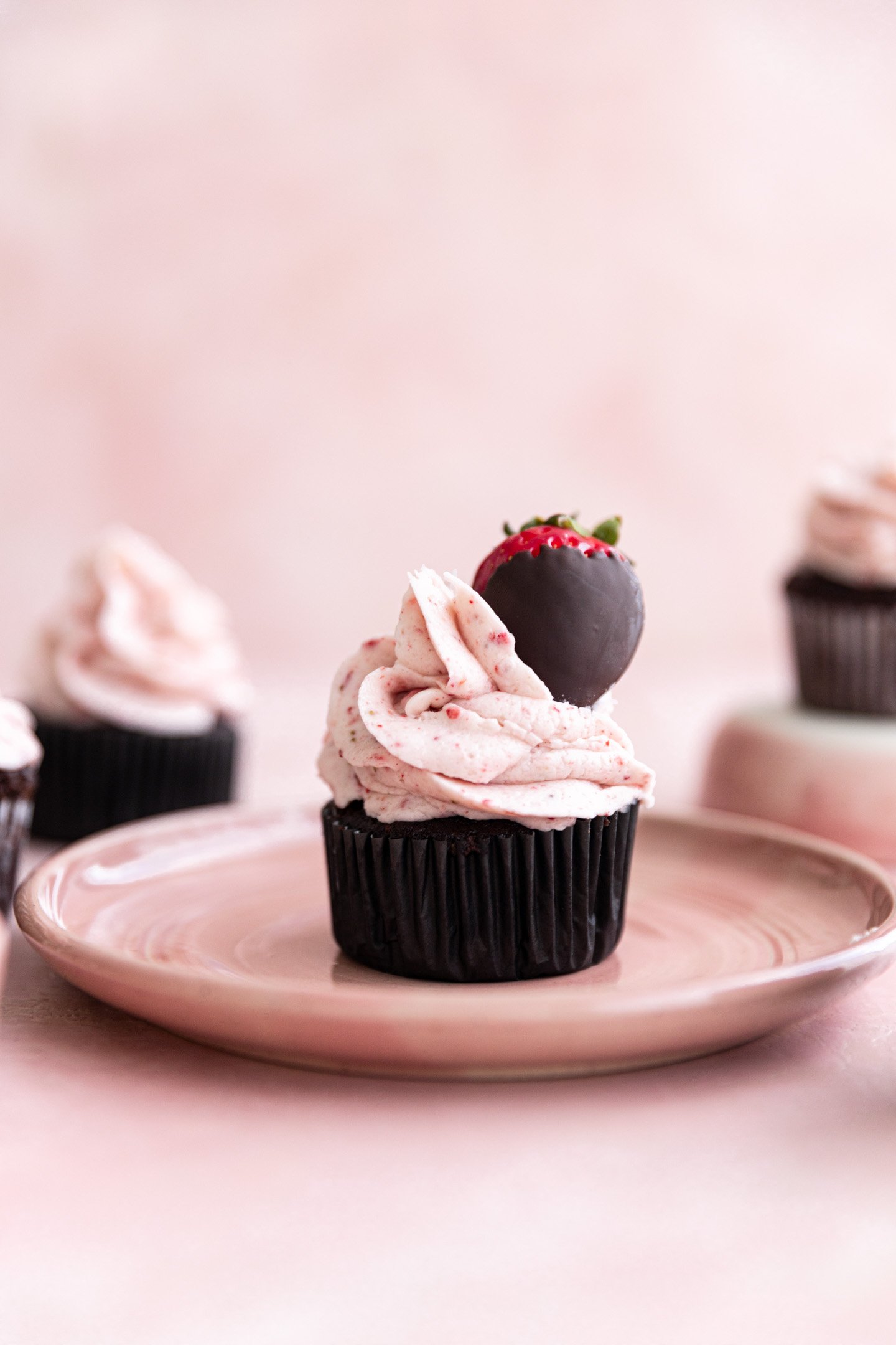 A chocolate strawberry cupcake topped with a chocolate covered strawberry.