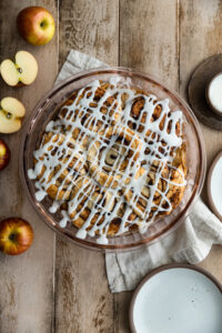 Cinnamon Roll Apple Pie in a pie dish on a wooden surface.