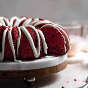 Cream cheese glaze drizzled over a red velvet bundt cake.