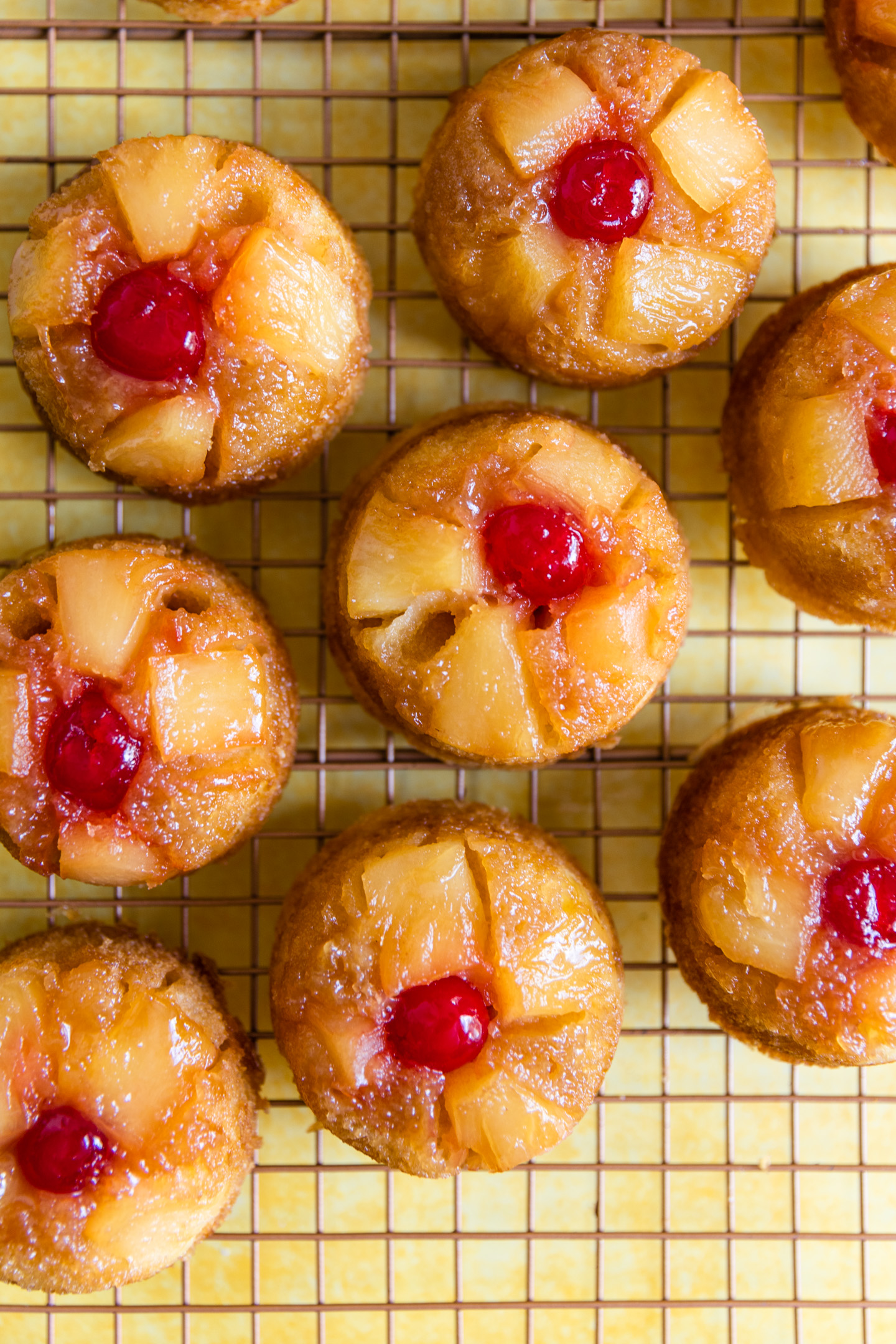 Pineapple upside down cupcakes on a wire rack.