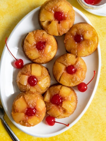 Pineapple upside down cupcakes on a white oval plate.