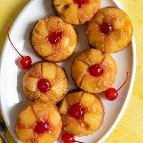 Pineapple upside down cupcakes on a white oval plate.