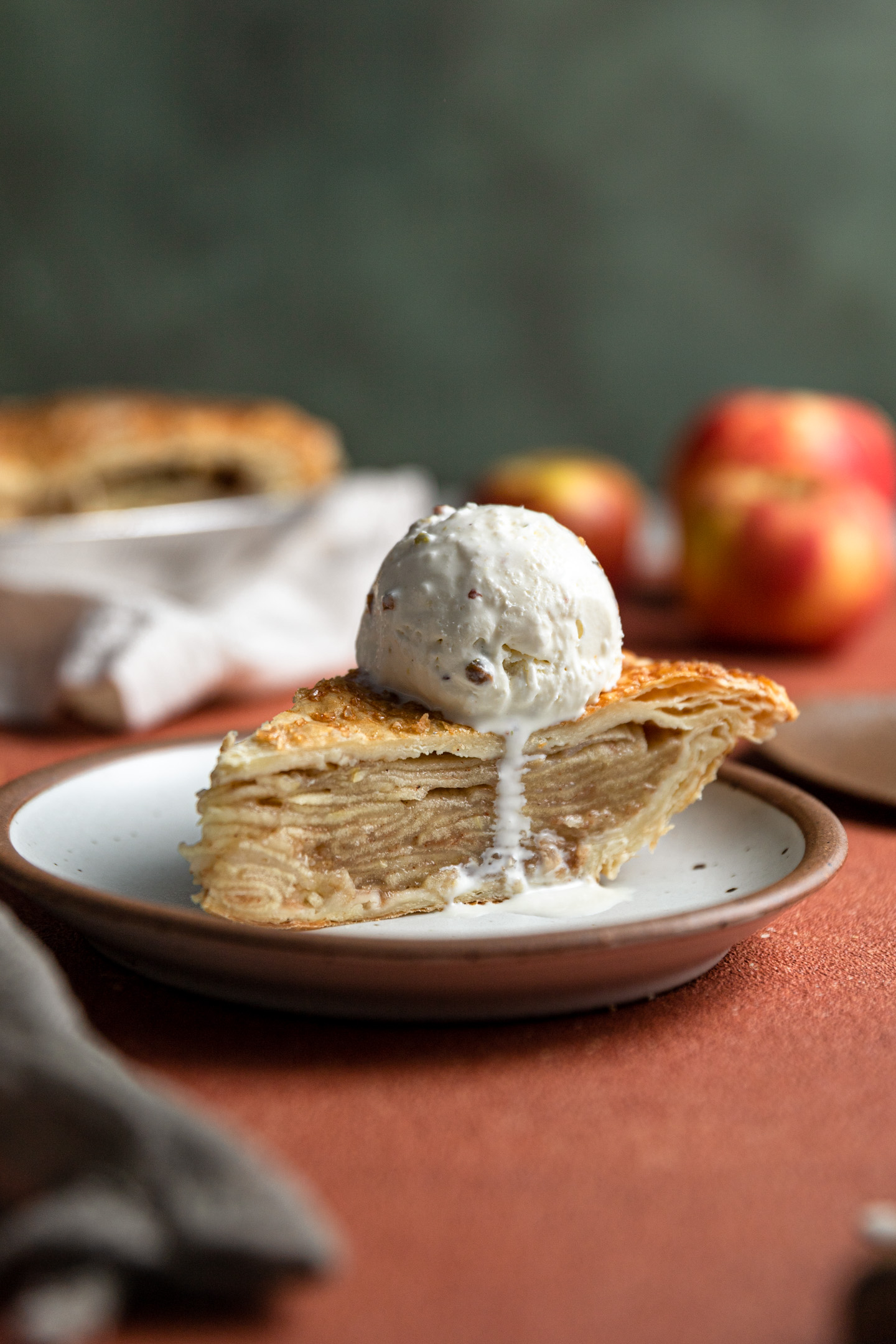 A slice of apple pie made with puff pastry with a scoop of ice cream on top.