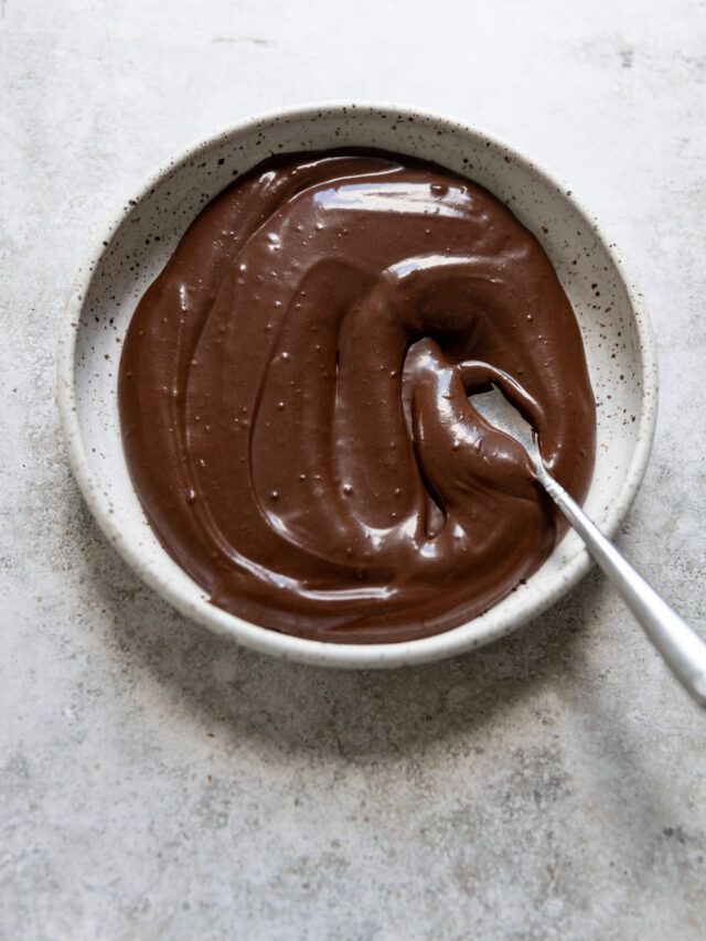 Chocolate glaze in a shallow bowl with a spoon.