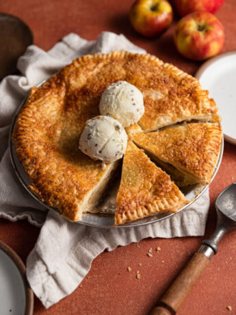 Ice cream on top of a cut apple pie.