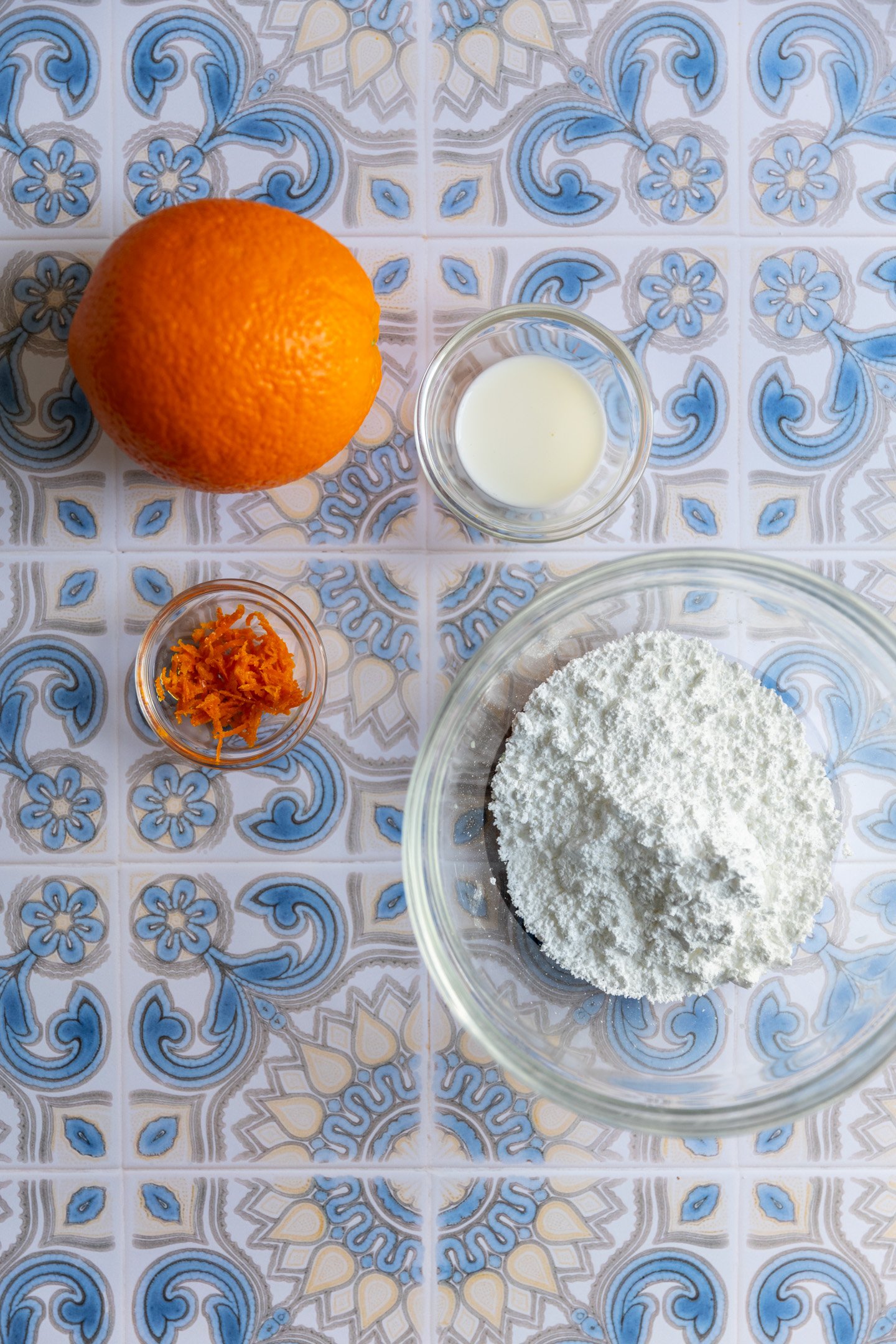 Ingredients for orange icing on a blue decorative surface.