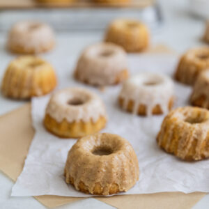 Mini iced bundt cakes on brown and white parchment paper.
