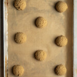 Cookie dough balls on a baking sheet lined with parchment paper.