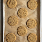 Baked chocolate chipless cookies on a parchment lined baking sheet.