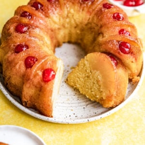 A pineapple upside down bundt cake with a slice cut and on it's side.