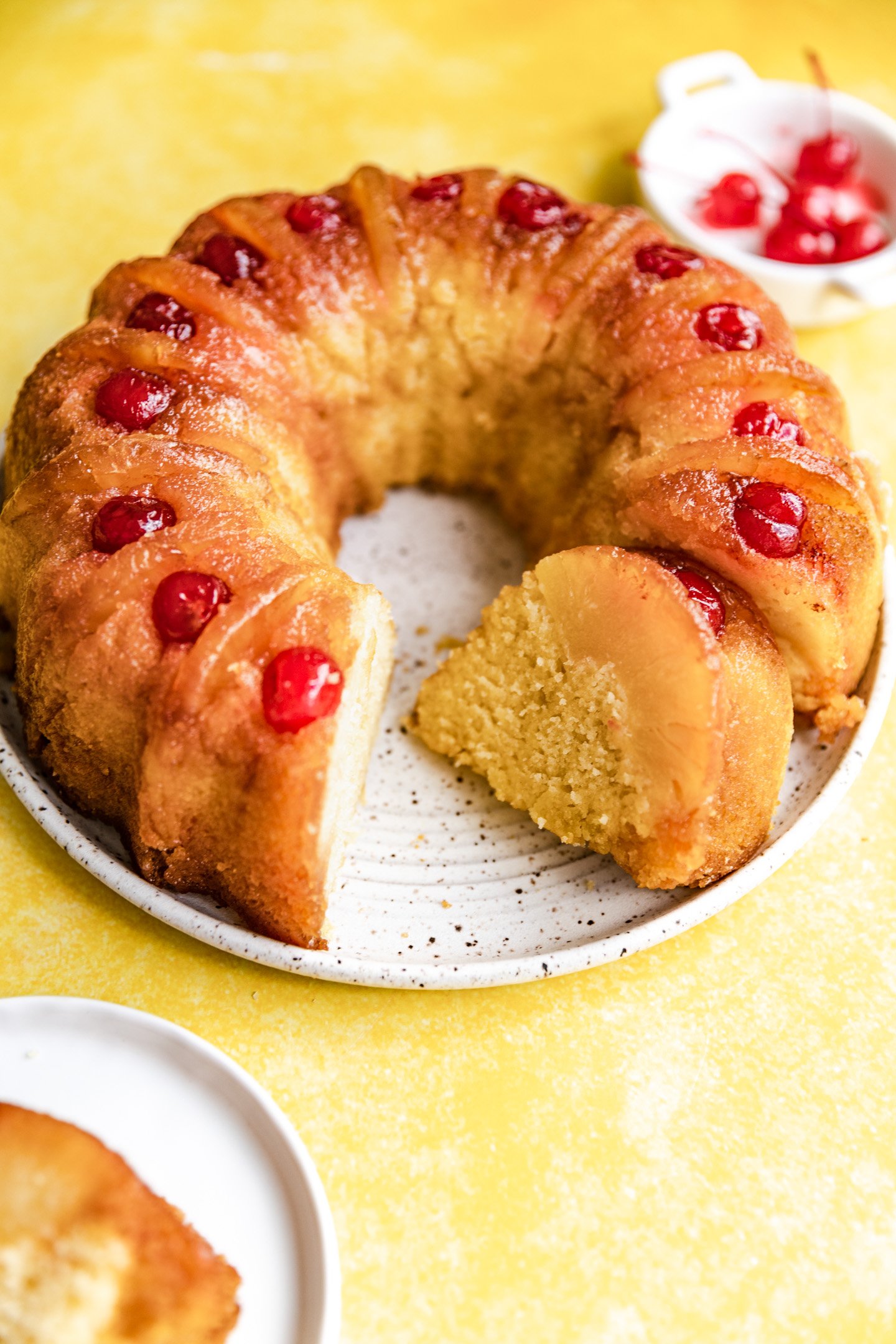 A pineapple upside down bundt cake with a slice cut and on it's side.