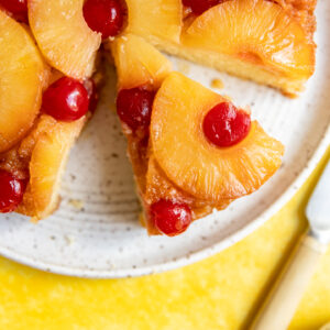 A slice of upside down pineapple cake cut on a white plate.