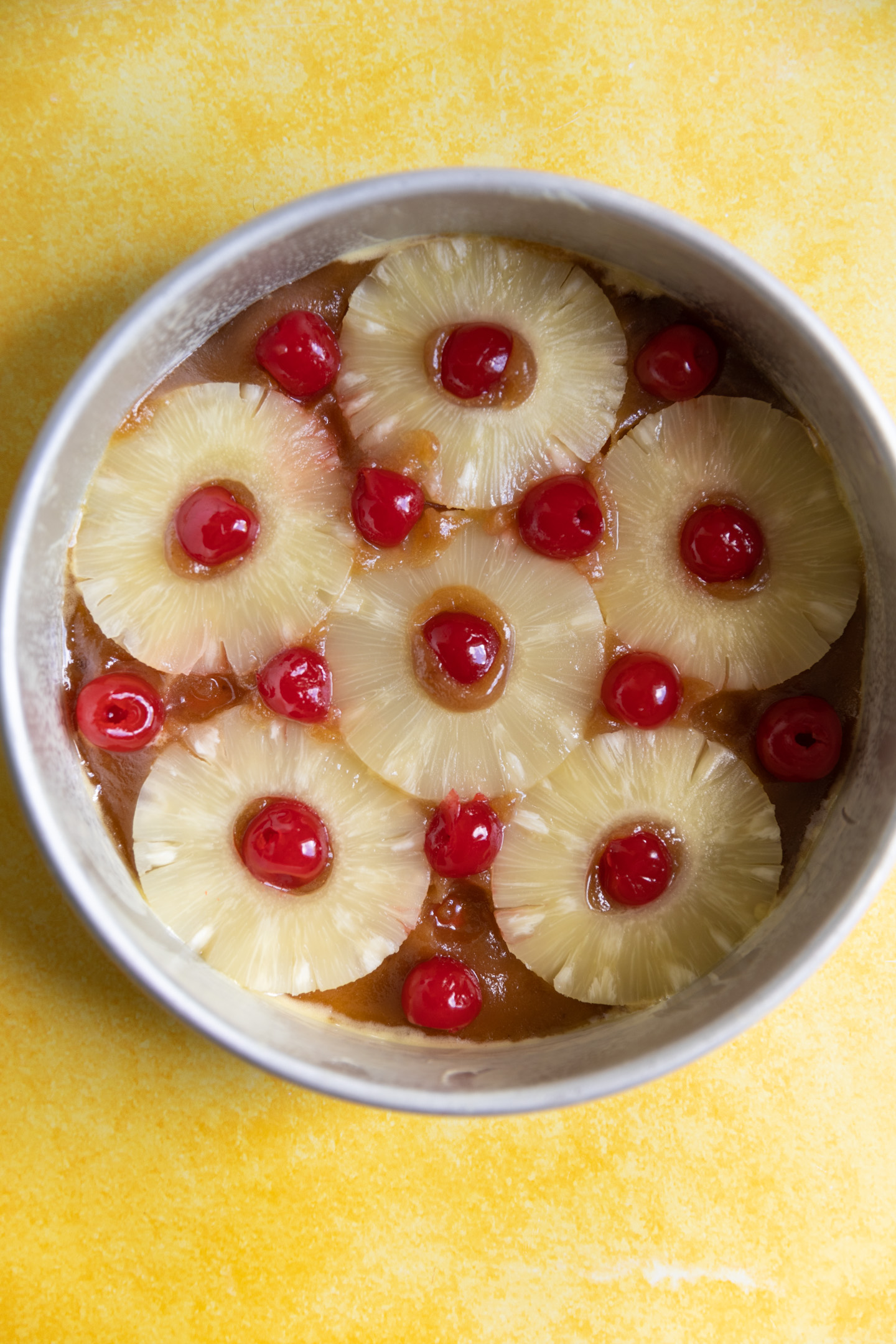 Pineapple rings and maraschino cherries in a cake pan.