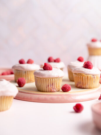 Raspberry cupcakes on an overturned pink plate.
