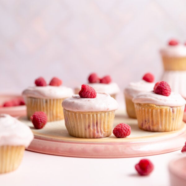Raspberry cupcakes on an overturned pink plate.