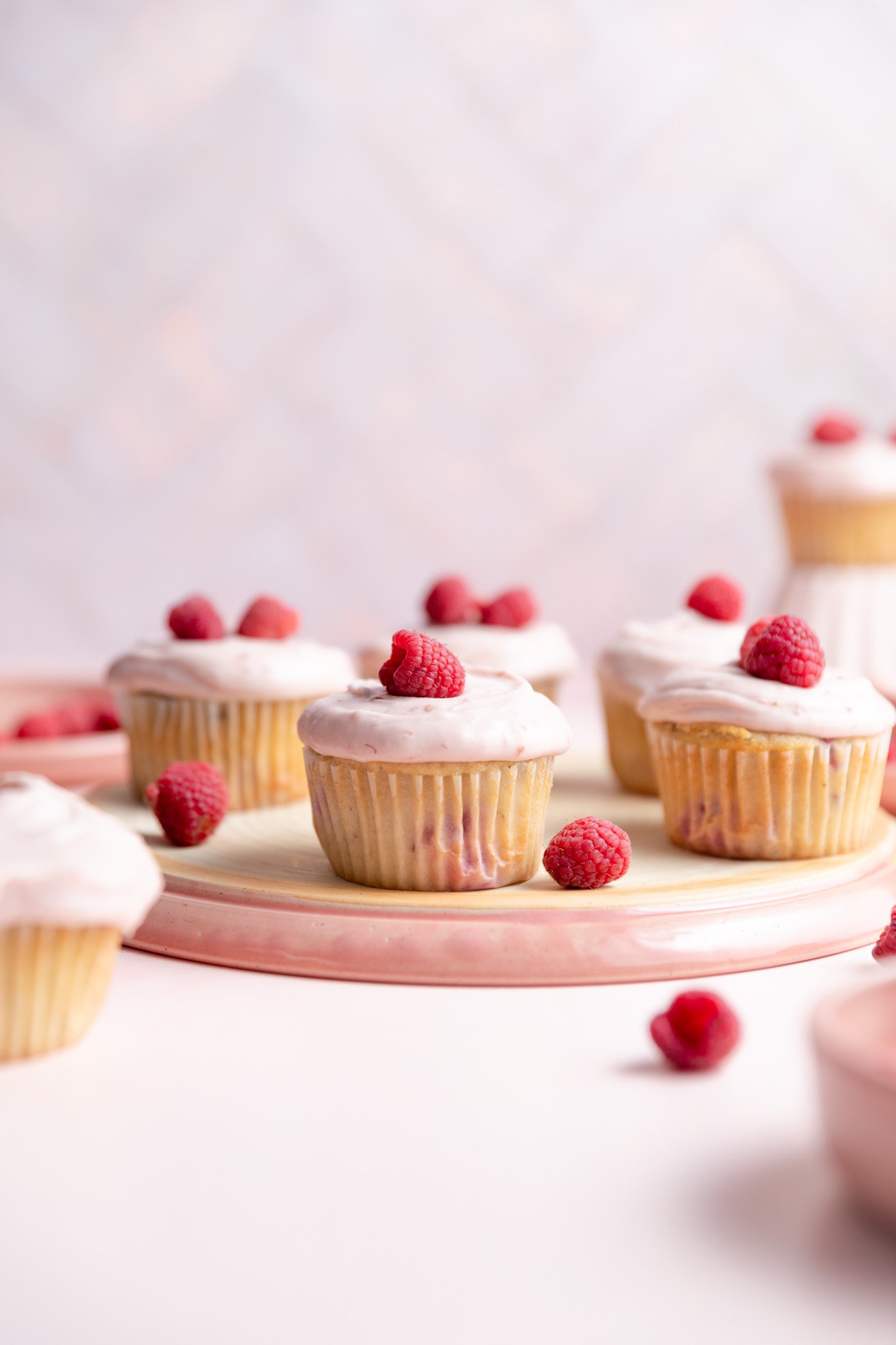 Raspberry cupcakes on an overturned pink plate.