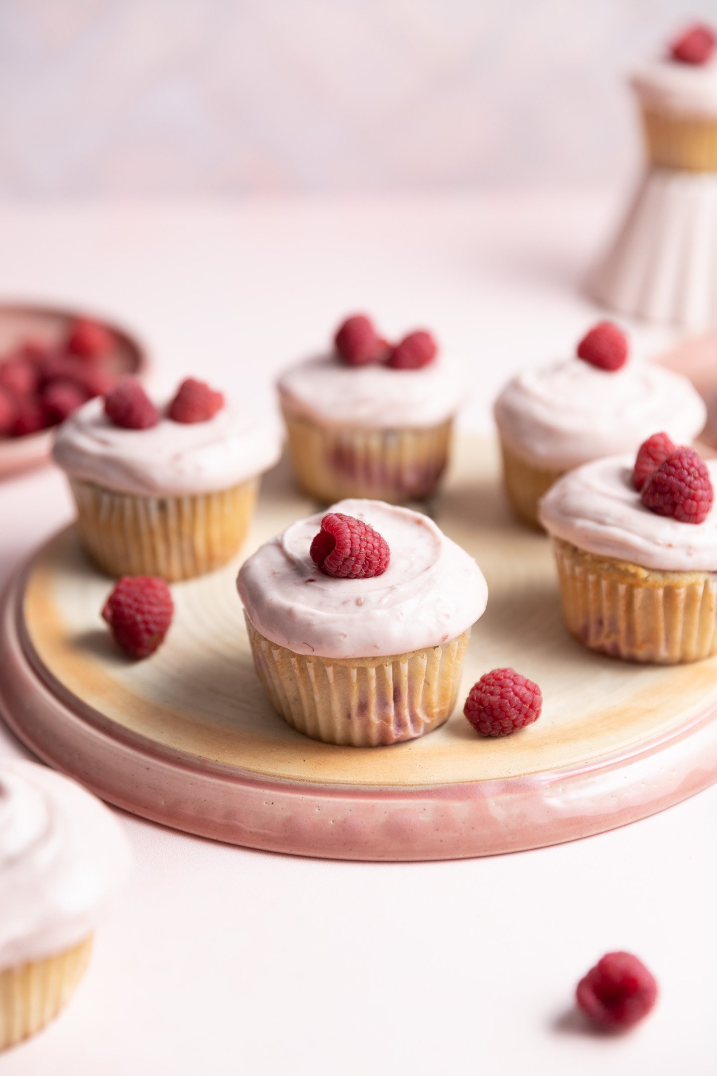 Raspberry cupcakes with raspberry cream cheese frosting on a pink plate.