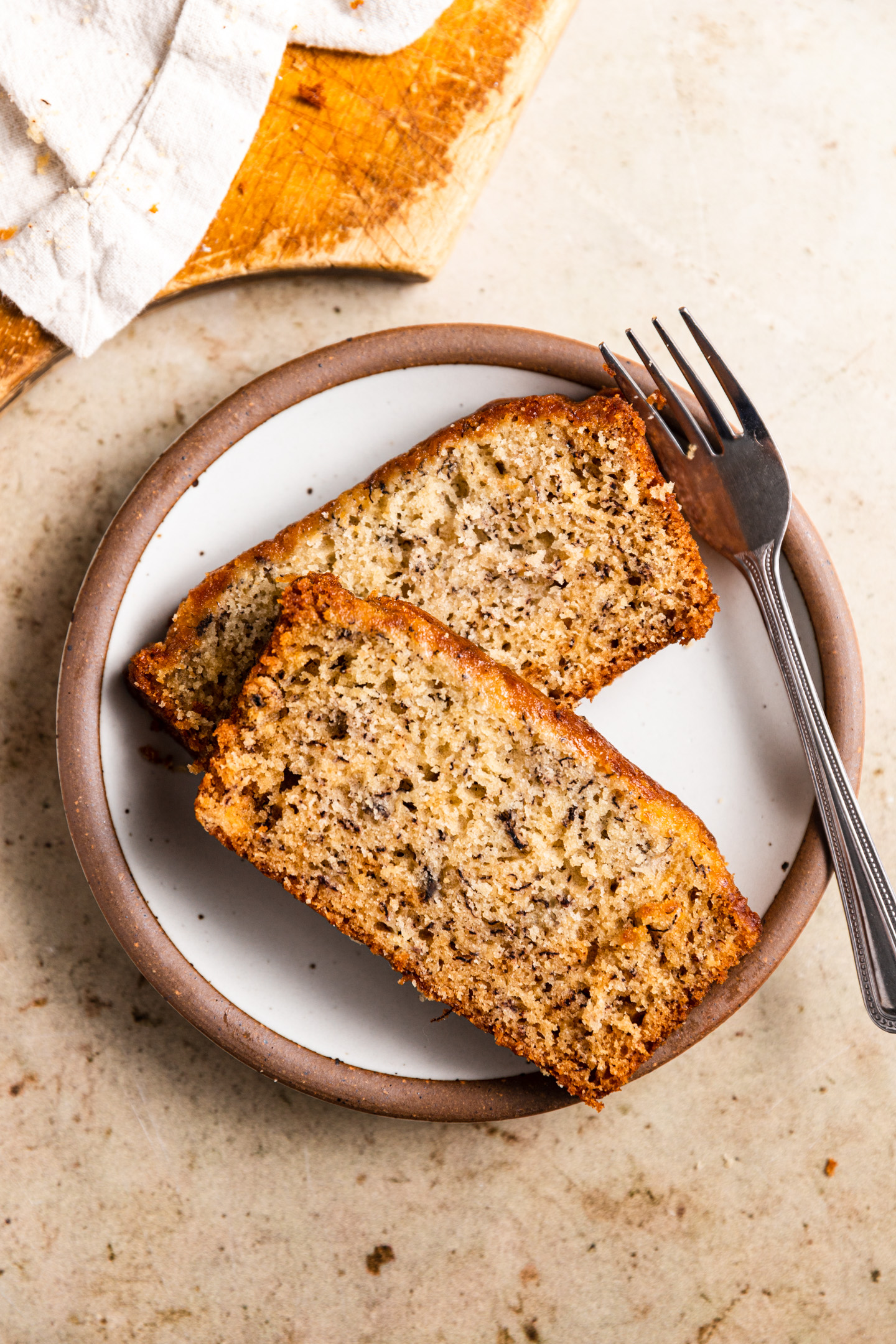 Two slices of banana bread on a plate next to a fork.