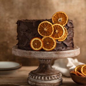 A chocolate orange cake frosted with chocolate frosting and garnished with dried orange slices.