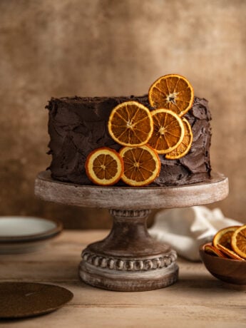 A chocolate orange cake frosted with chocolate frosting and garnished with dried orange slices.
