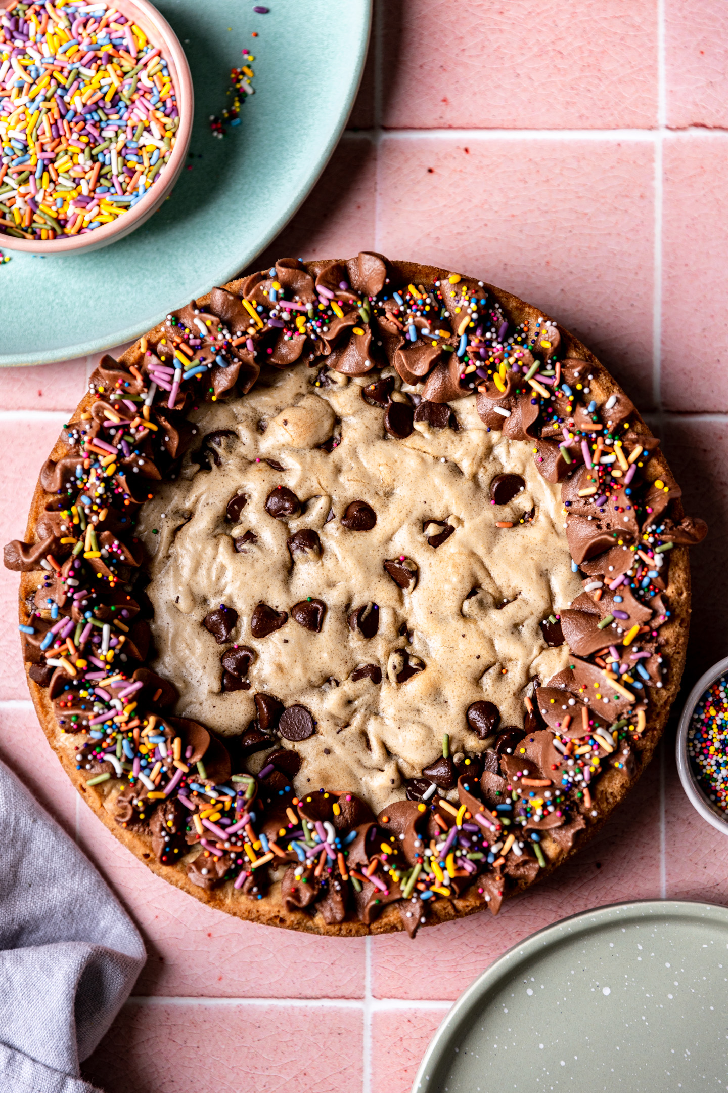 A chocolate chip cookie cake topped with vegan chocolate frosting.