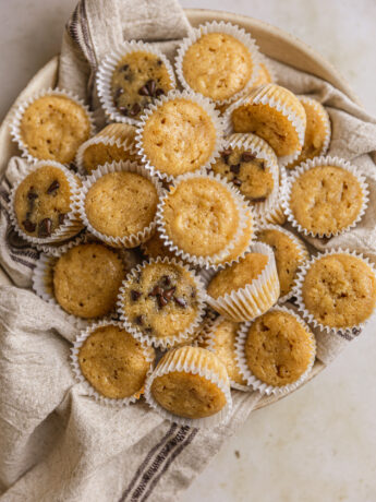 Mini banana muffins in a bowl lined with a linen napkin.