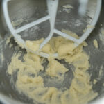 Creamed butter, powdered sugar and granulated sugar in a mixing bowl with a paddle attachment.