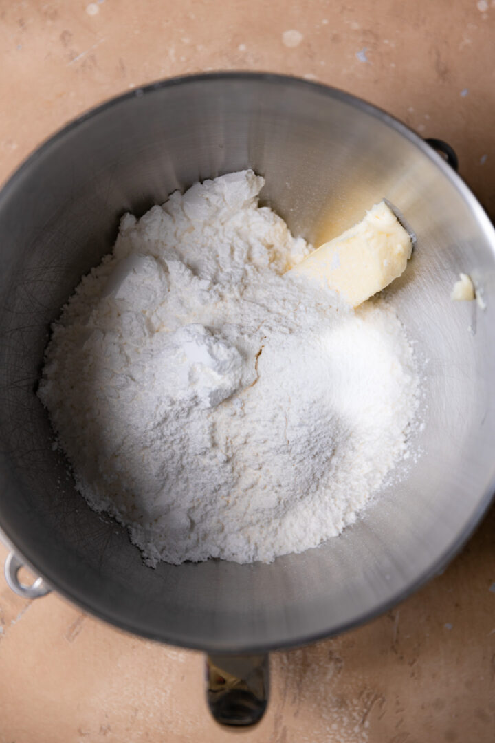 Butter and dry ingredients in a stainless steel mixing bowl.