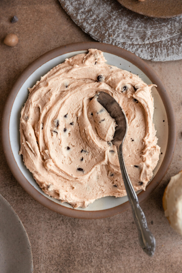 A plate of cookie dough frosting smeared with a spoon.