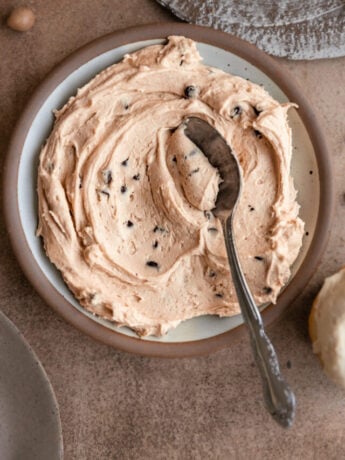A plate of cookie dough frosting smeared with a spoon.