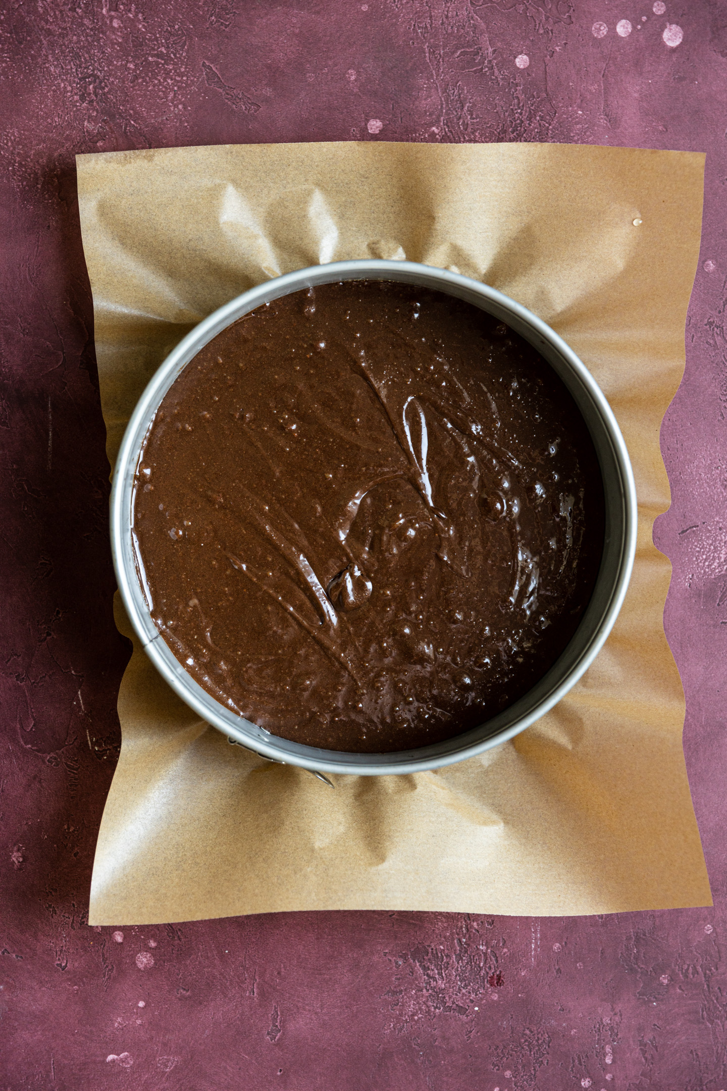The bottom layer of a chocolate mousse cake batter in a springform pan.