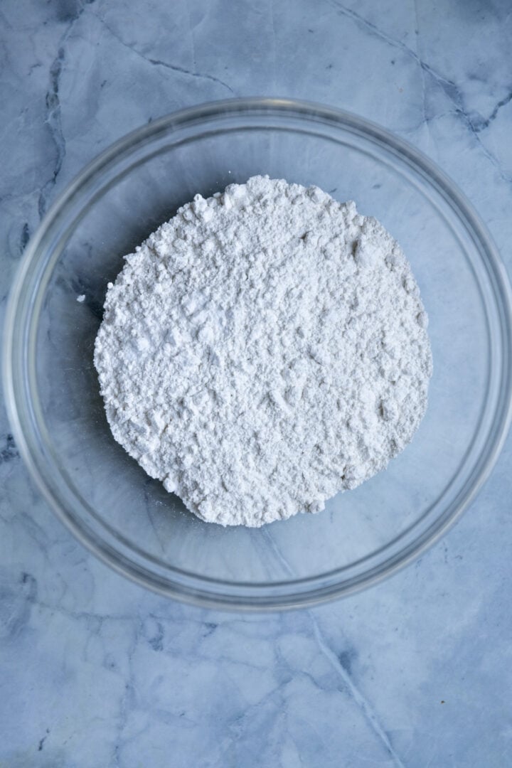 Dry ingredients for cupcakes in a bowl on a blue surface.