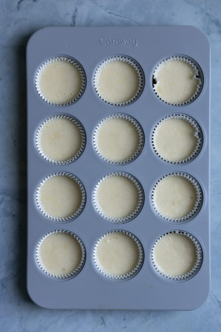 Cupcake batter in a gray muffin tin.