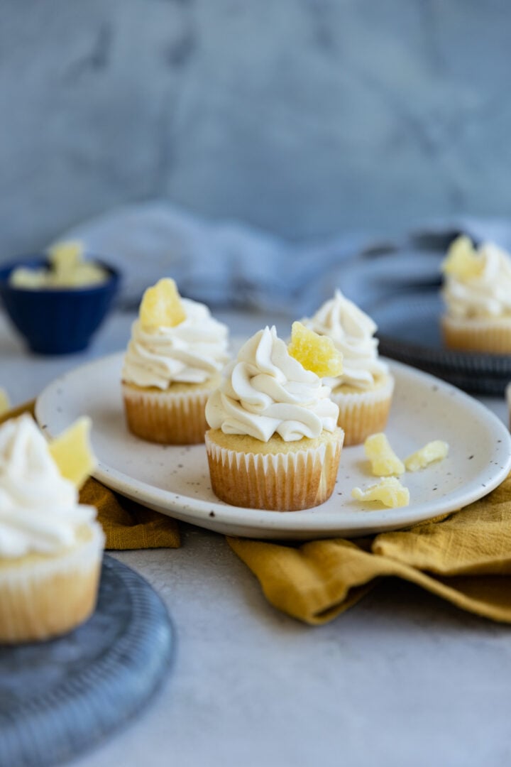 Three pineapple cupcakes on a small platter on top of a yellow napkin.