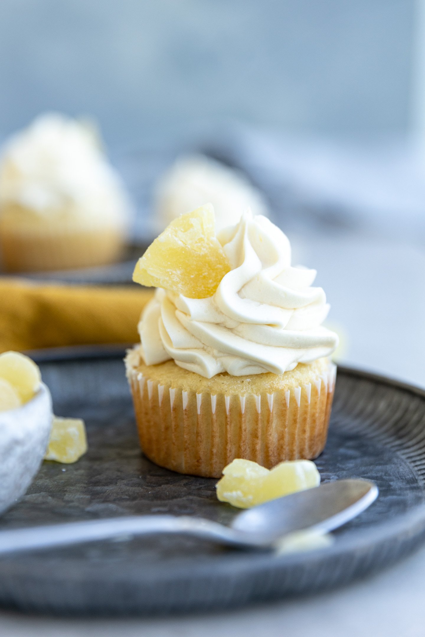 A pineapple cupcake garnished with a sugared pineapple on top of blue plates. 