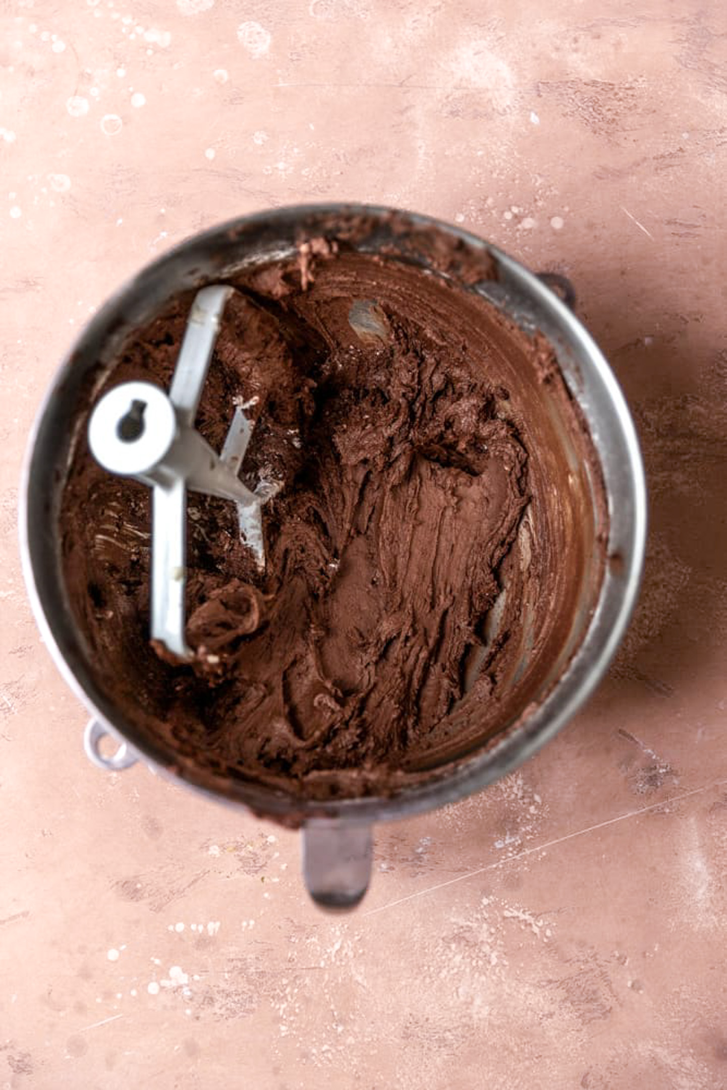 Chocolate frosting mixed in a mixing bowl with a paddle attachment,