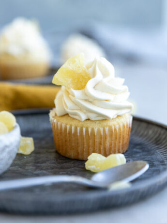 A pineapple cupcake garnished with a sugared pineapple on top of blue plates.