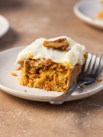A piece of a carrot pineapple cake on a small plate next to a fork.